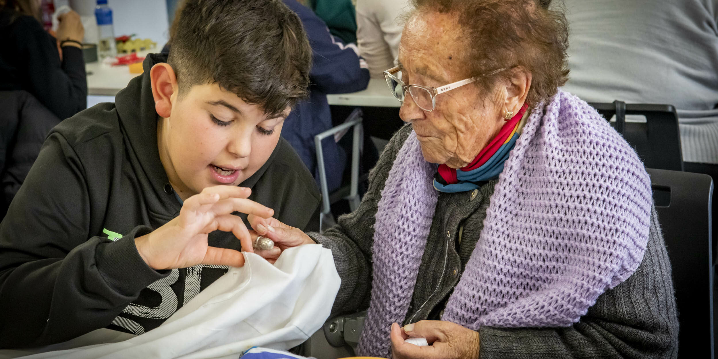 Abuela y niño cosiendo exposición Pendiebtes de un hilo Famsi